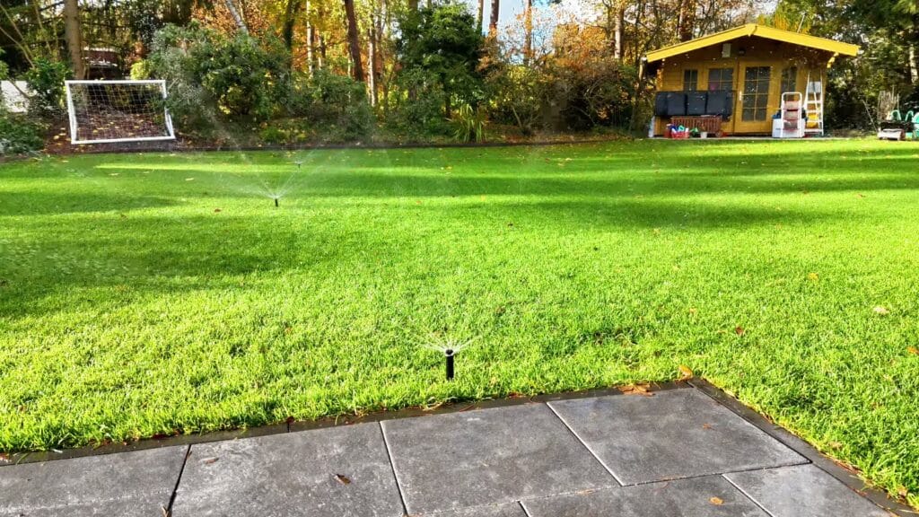 Fertig bewässerter Garten mit grüner Rasenfläche und laufenden Regnern