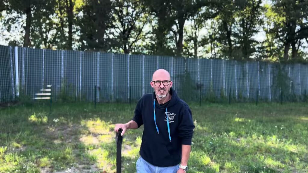 Mitarbeiter von Bewässerungsbox steht mit einem Spaten auf einer Rasenfläche